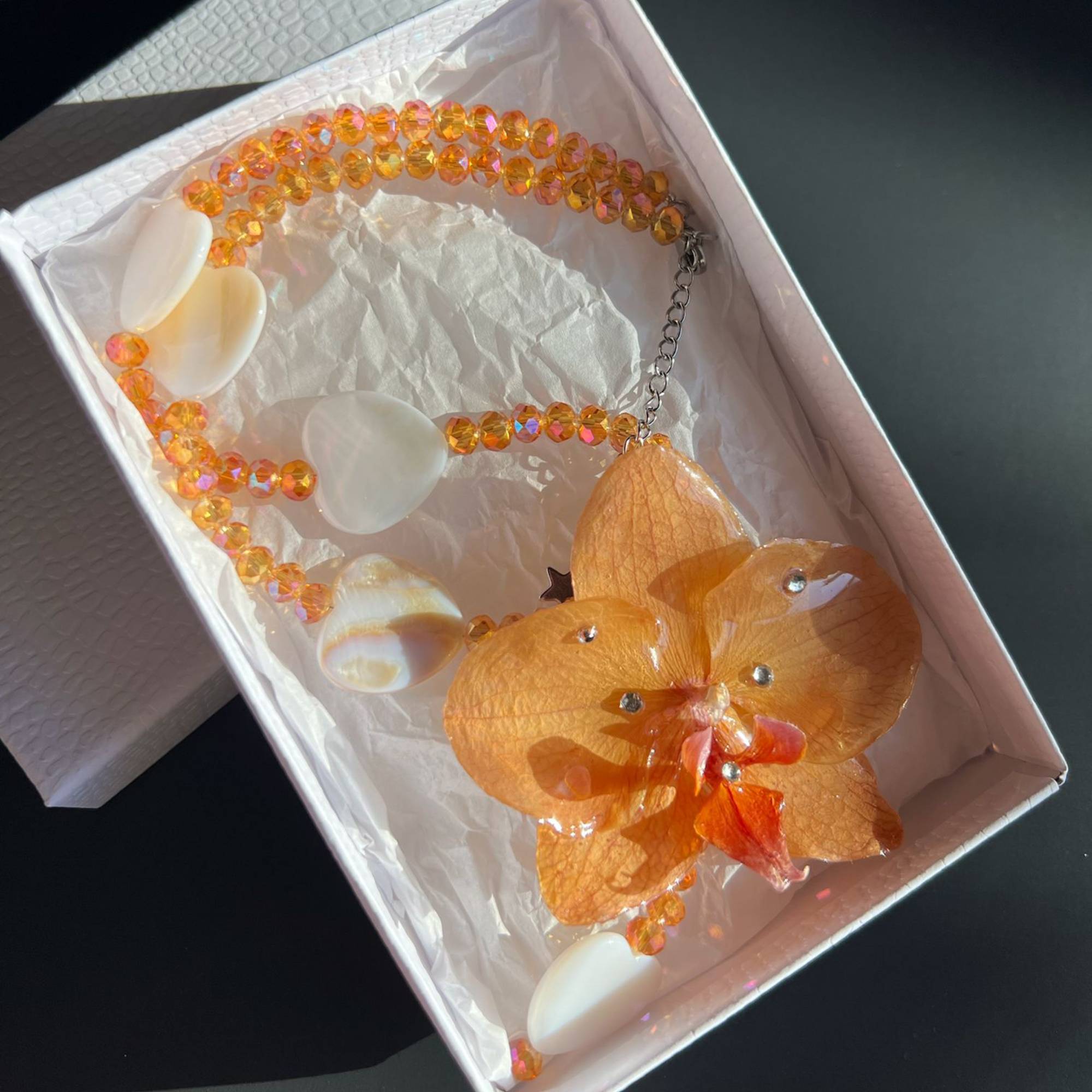 Real orange orchid flower necklace, handmade with resin-preserved tropical bloom. Features natural heart seashells and glass beads. Unique floral pendant jewelry, beach-inspired gift for her, botanical statement necklace, eco-friendly nature accessory, boho summer jewelry, one-of-a-kind artisan gift.