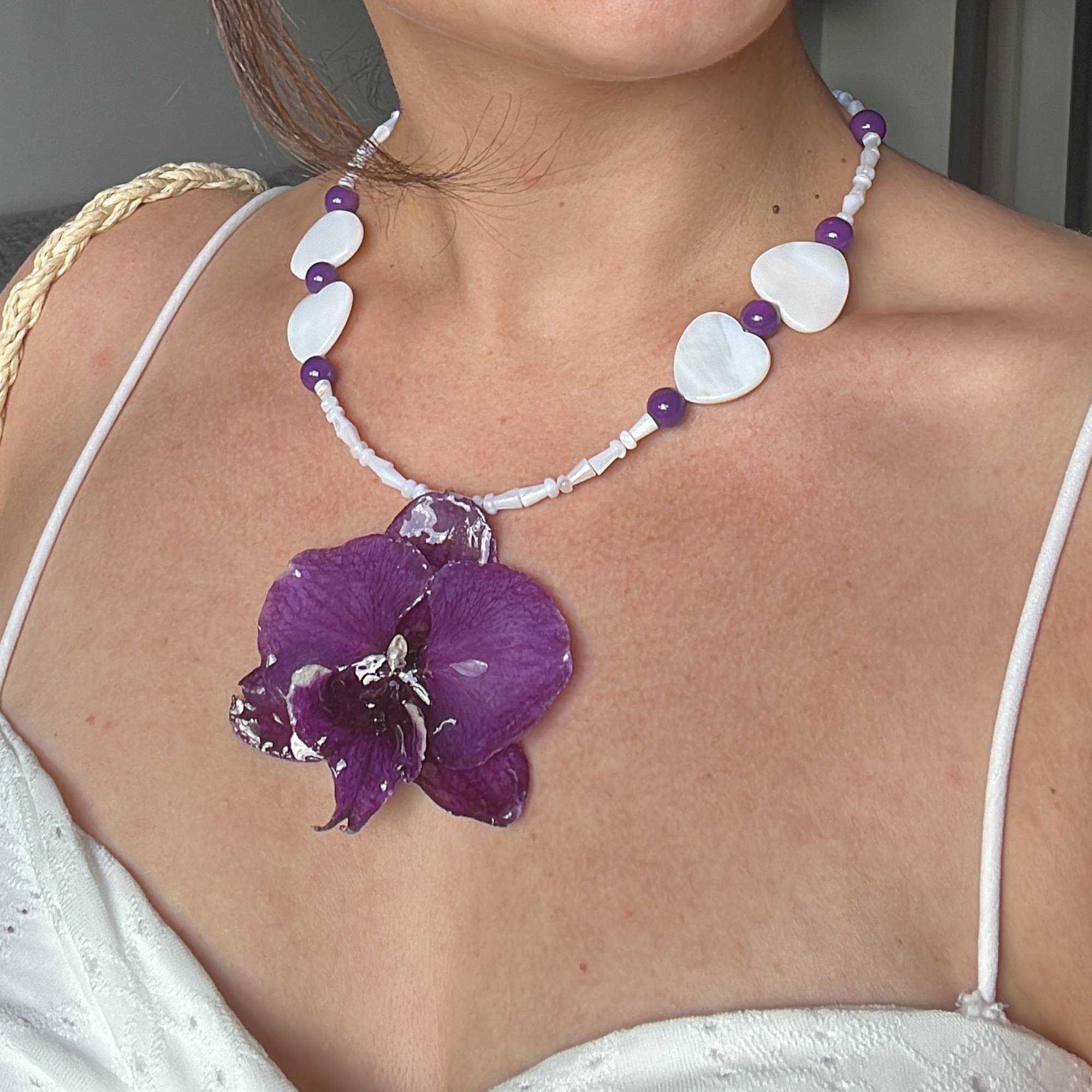 Real purple orchid pendant necklace preserved in resin, accented with purple glass beads and heart-shaped shells. Handmade floral jewelry, unique botanical gift for her. One-of-a-kind nature-inspired accessory, perfect for birthdays, anniversaries, or beach weddings.