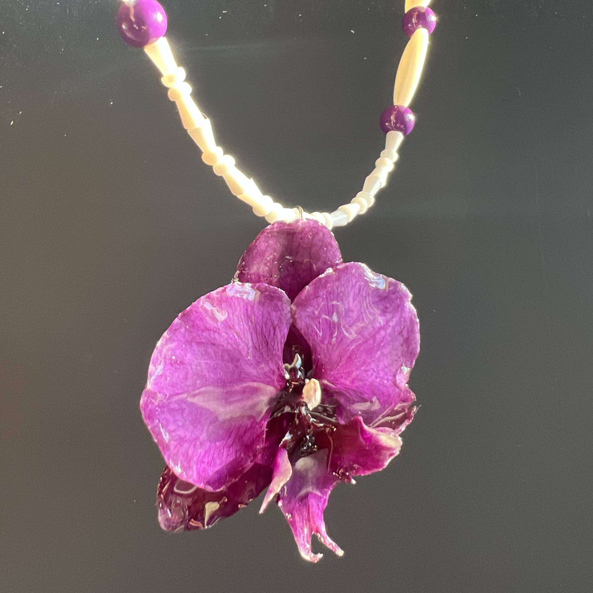 Real purple orchid pendant necklace preserved in resin, accented with purple glass beads and heart-shaped shells. Handmade floral jewelry, unique botanical gift for her. One-of-a-kind nature-inspired accessory, perfect for birthdays, anniversaries, or beach weddings.