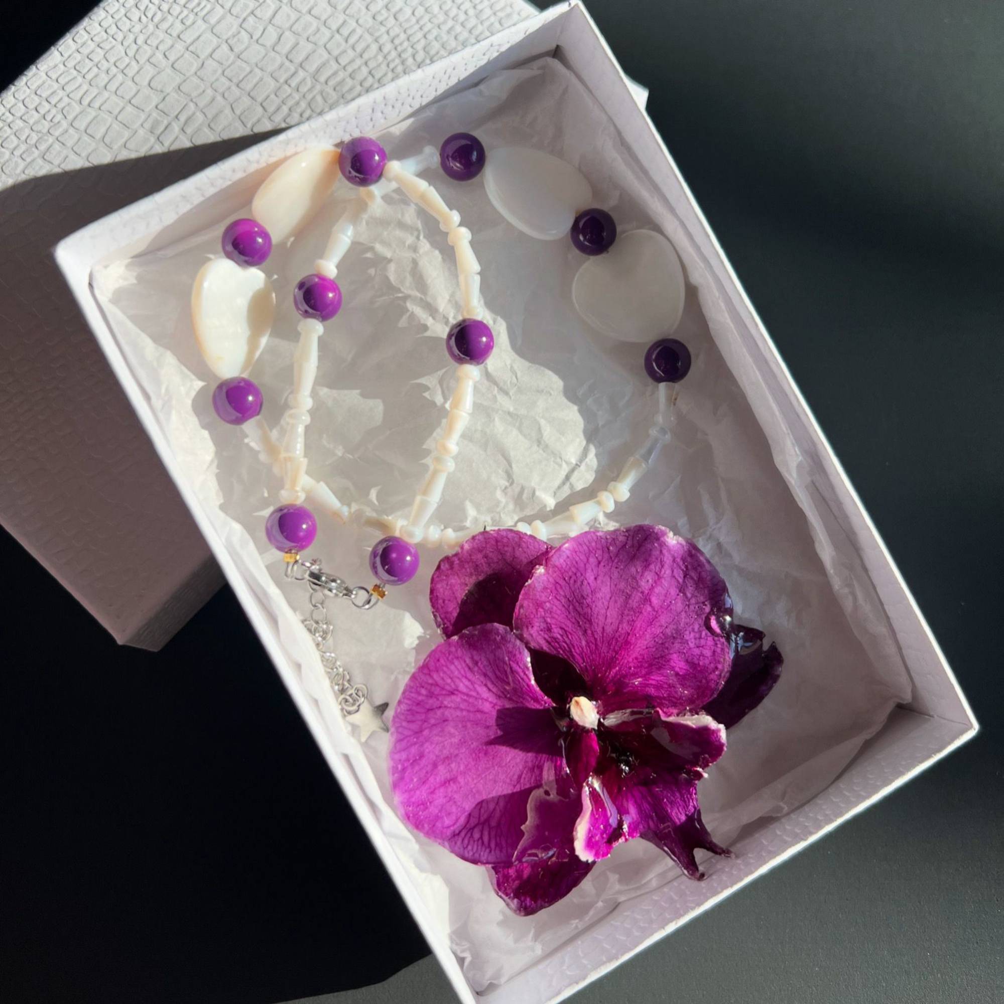 Real purple orchid pendant necklace preserved in resin, accented with purple glass beads and heart-shaped shells. Handmade floral jewelry, unique botanical gift for her. One-of-a-kind nature-inspired accessory, perfect for birthdays, anniversaries, or beach weddings.