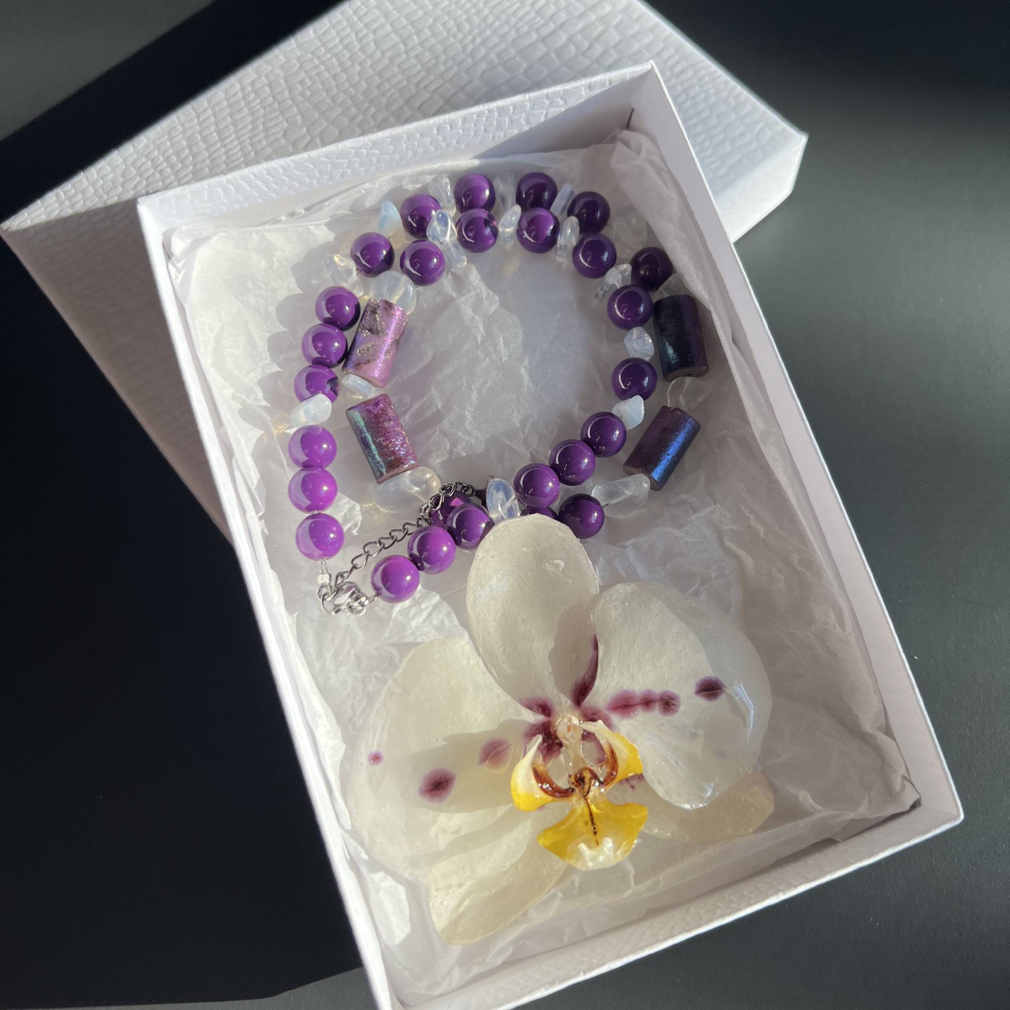 Handmade necklace featuring a real white and purple orchid flower, naturally dried and preserved in clear resin. Accented with white and purple glass beads, this unique floral pendant is a one-of-a-kind piece of botanical jewelry. Perfect gift for her, ideal for nature lovers, orchid enthusiasts, and fans of boho, garden, or eco-friendly fashion. Great for birthdays, anniversaries, bridesmaids, and spring or summer outfits. Real flower necklace, resin jewelry for women.