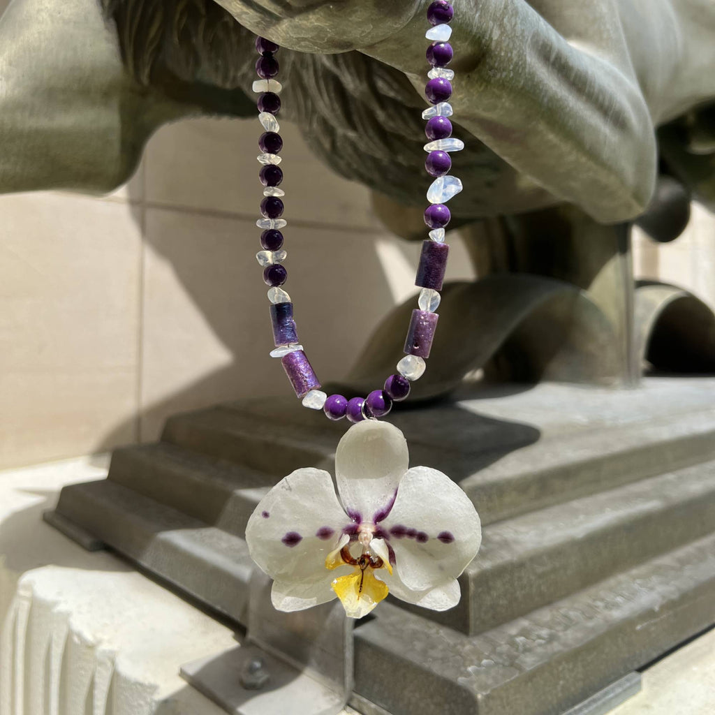 Handmade necklace featuring a real white and purple orchid flower, naturally dried and preserved in clear resin. Accented with white and purple glass beads, this unique floral pendant is a one-of-a-kind piece of botanical jewelry. Perfect gift for her, ideal for nature lovers, orchid enthusiasts, and fans of boho, garden, or eco-friendly fashion. Great for birthdays, anniversaries, bridesmaids, and spring or summer outfits. Real flower necklace, resin jewelry for women.