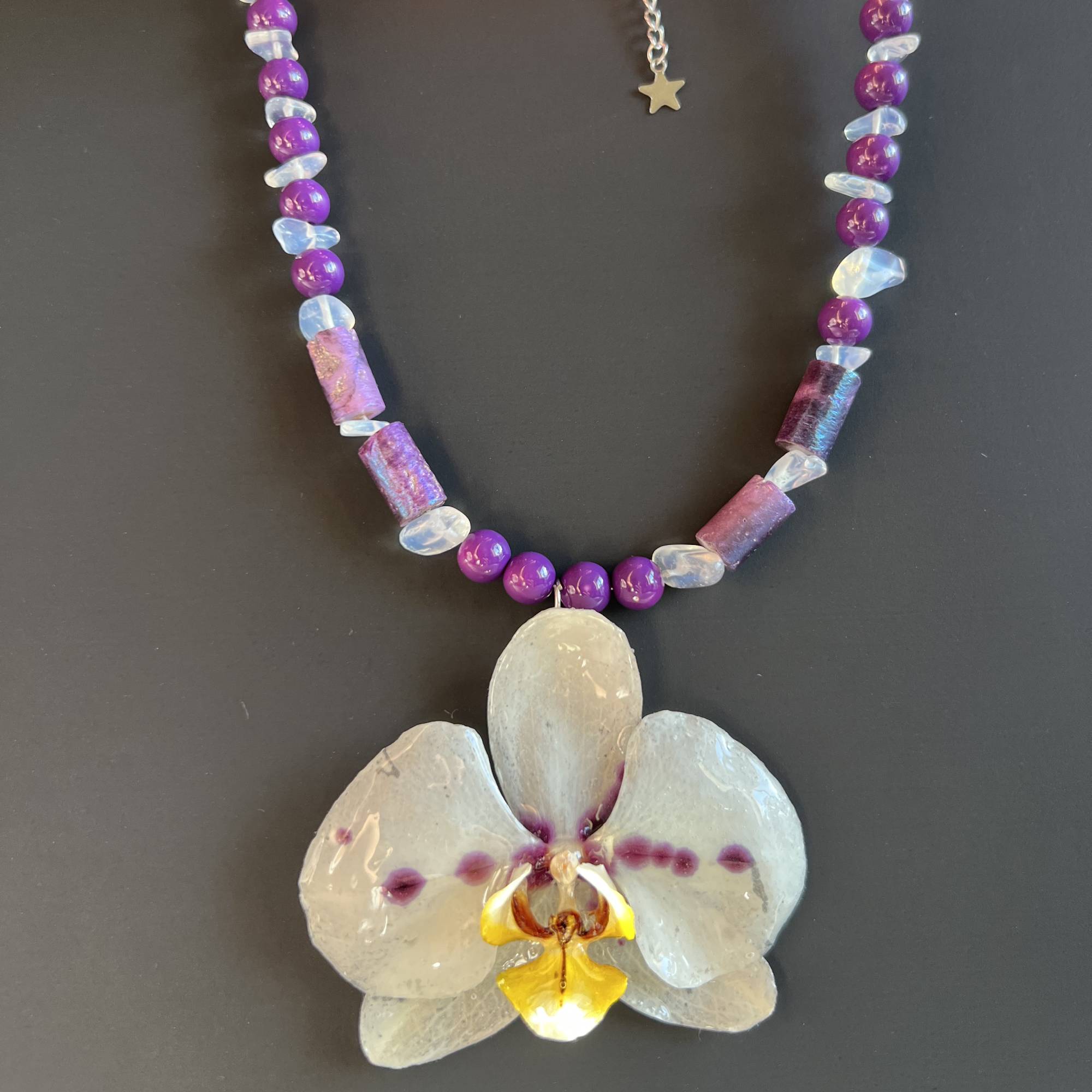 Handmade necklace featuring a real white and purple orchid flower, naturally dried and preserved in clear resin. Accented with white and purple glass beads, this unique floral pendant is a one-of-a-kind piece of botanical jewelry. Perfect gift for her, ideal for nature lovers, orchid enthusiasts, and fans of boho, garden, or eco-friendly fashion. Great for birthdays, anniversaries, bridesmaids, and spring or summer outfits. Real flower necklace, resin jewelry for women.